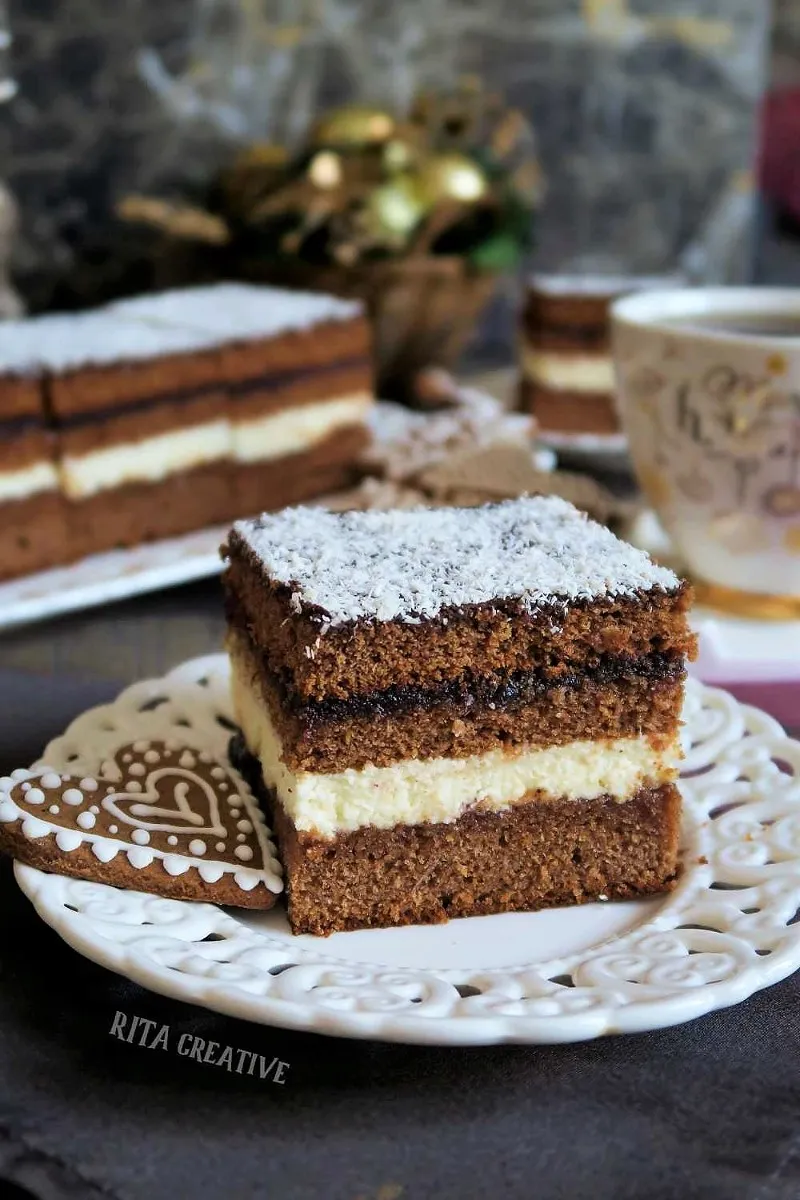 Piernik Herbaciany z kremem grysikowym i powidłami śliwkowymi na talerzyku deserowym.