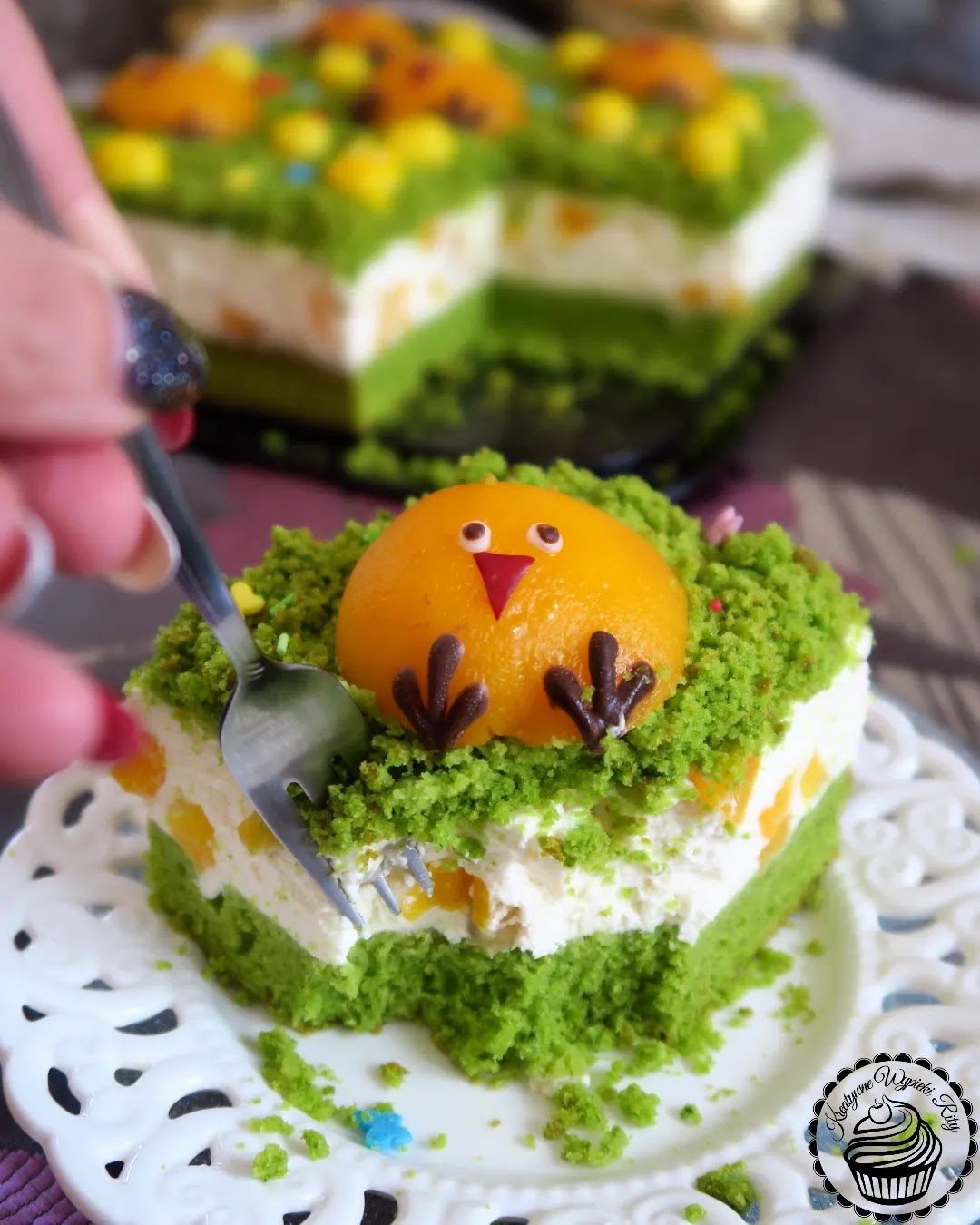 Pomysł na wielkanocny deser – Łąka z Kurczaczkami Wielkanocne ciasto szpinakowe udekorowane brzoskwiniami w kształcie kurczaczków, jajeczkami i cukrowymi motylkami.