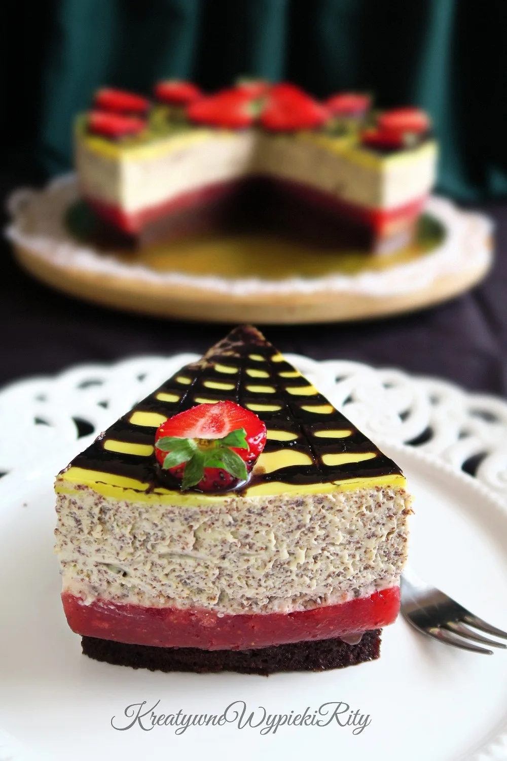 Kawałek torcika pokazujący warstwy: czekoladowy biszkopt, mus truskawkowy i krem ajerkoniakowy