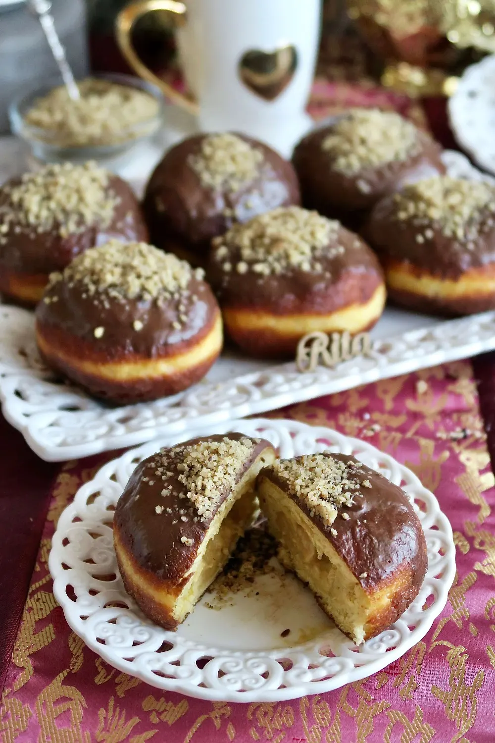 Przekrój pączka na talerzyku – widoczna lśniąca polewa i drobno zmielone orzechy.