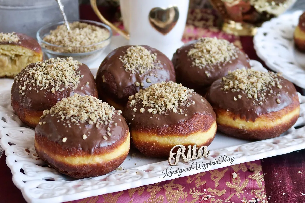 Gotowe pączki z budyniem karmelowym na talerzykach, przygotowane do podania na Tłusty Czwartek.