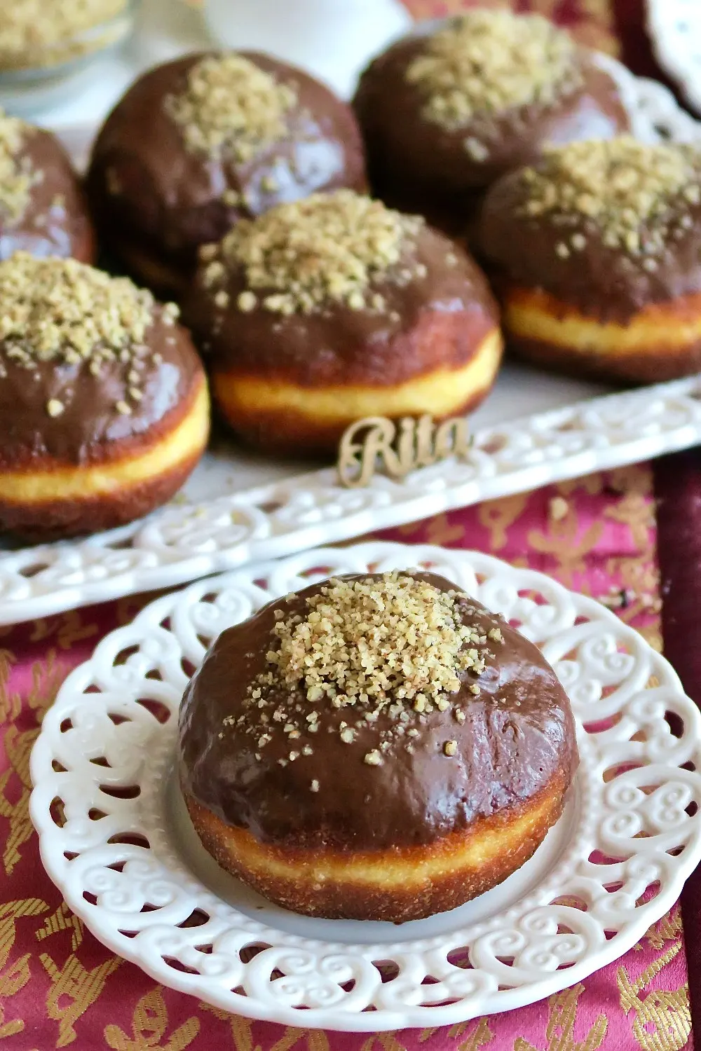 Domowe pączki z budyniem karmelowym i orzechami ułożone na talerzyku.