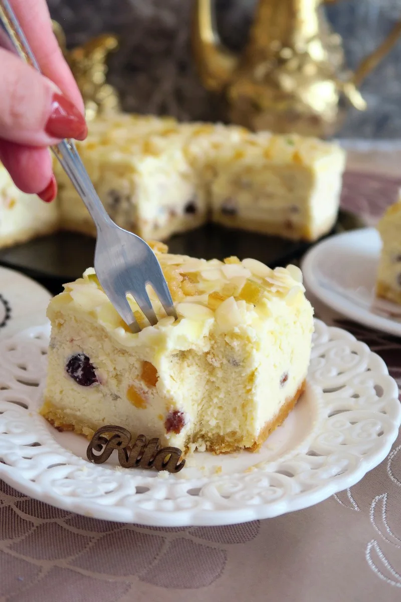 Sernik z bakaliami na kruchym spodzie z mleczną polewą Kremowy sernik z bakaliami na kruchym spodzie, z mleczną polewą, migdałami i aromatyczną skórką cytrusową