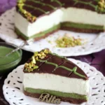 Sernik Dubajski z pistacjami – kremowy torcik na spodzie z ciasteczek, udekorowany polewą czekoladową, pistacjami i lukrem pistacjowym.
