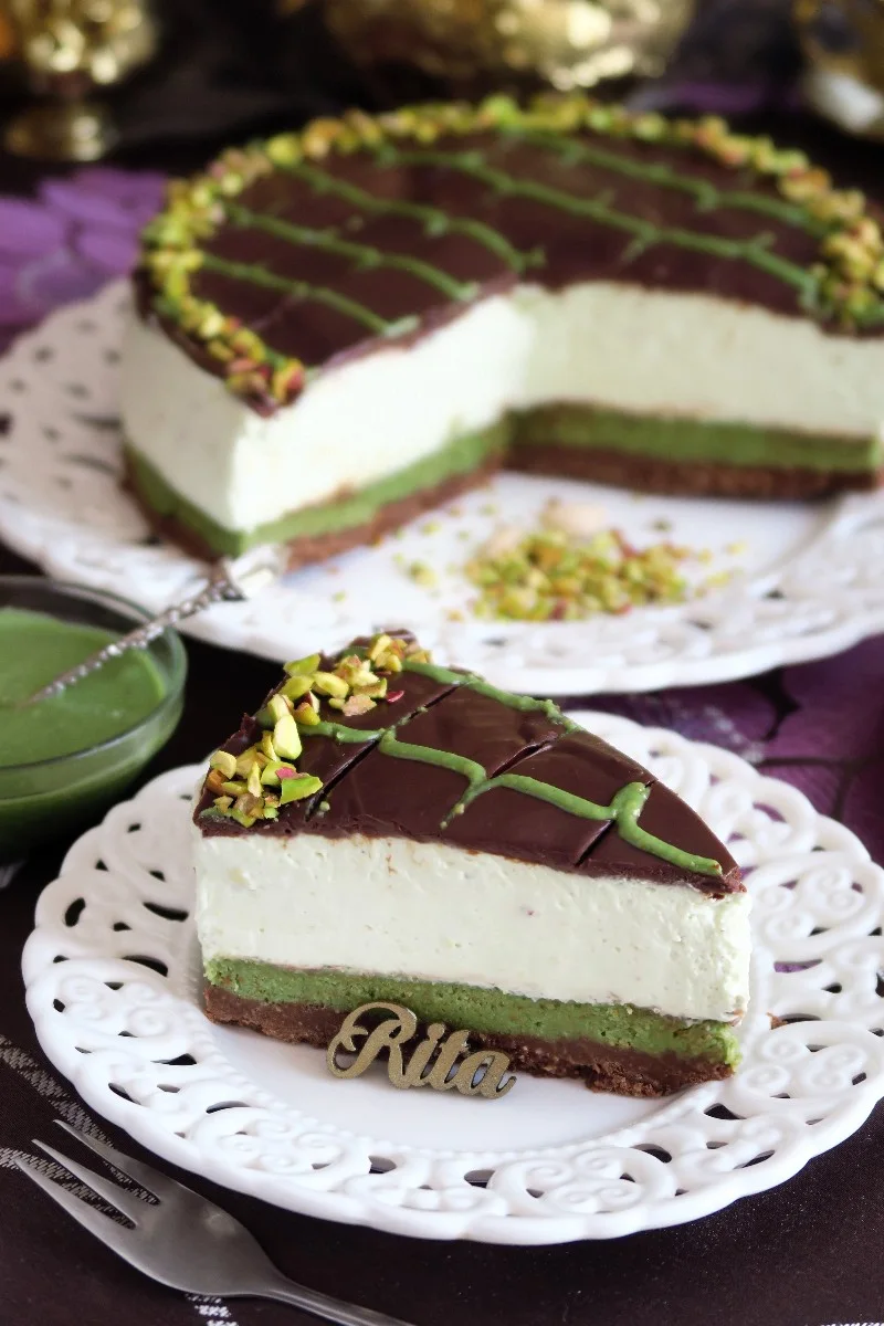 Sernik Dubajski z pistacjami – kremowy torcik na spodzie z ciasteczek, udekorowany polewą czekoladową, pistacjami i lukrem pistacjowym.