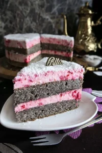 Zbliżenie na bok torcika makowego, widoczna wilgotna struktura kremu z malinami i posypka z kokosa.