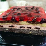 Makowiec z wiśniami w prostokątnej formie pokryty błyszczącą galaretką wiśniową z całymi owocami, idealne ciasto makowe z wiśniami na święta